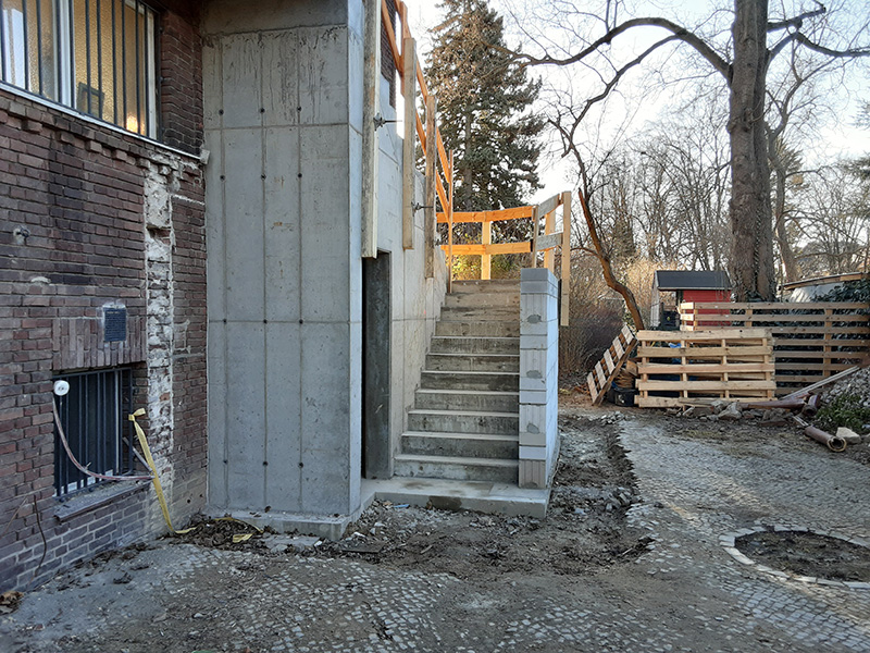 Stahlbetontreppe, zweiläufig mit Zwischenpodest in Ortbetonbauweise, Auflagerwände aus Beton und Mauerwerk, als Fluchttreppe nachträglich an Außenwand