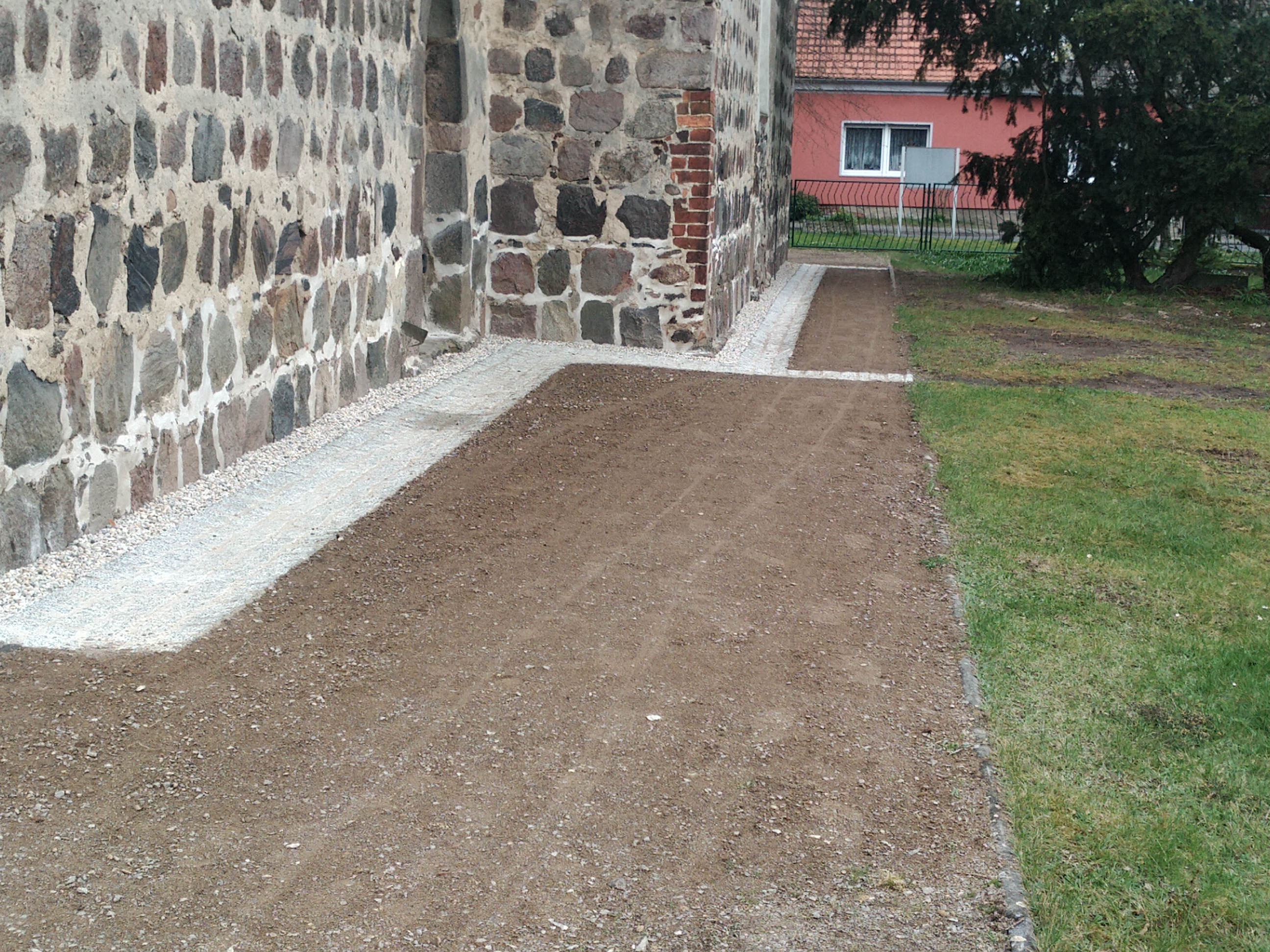 Herstellung eines Kieselstreifens und Natursteinpflasterrinne als Regenwasserabfluss und Wegbefestigung über gebundene Wegedecke